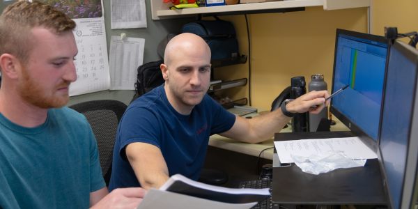 Nathan Janiczek pointing to computer and working alongside a team member.